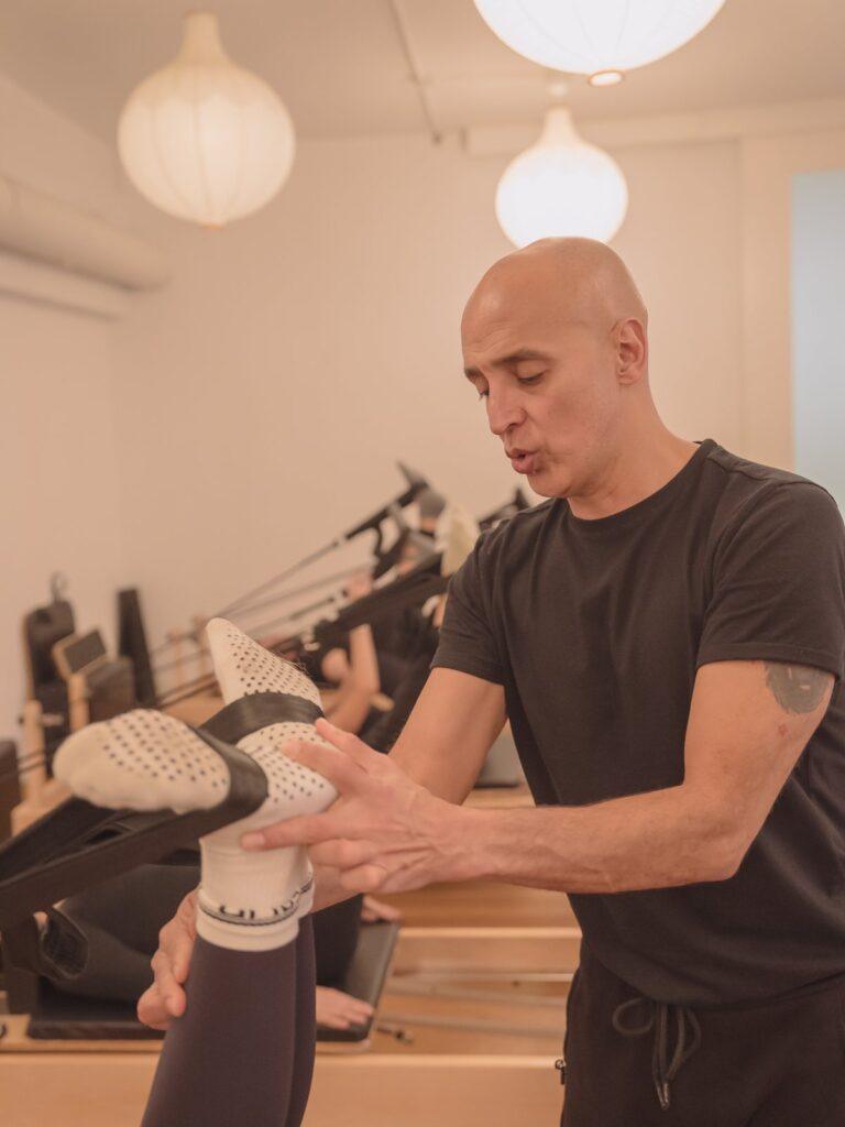 Instructor ajustando la posición de la pierna sobre el reformer en Madrid